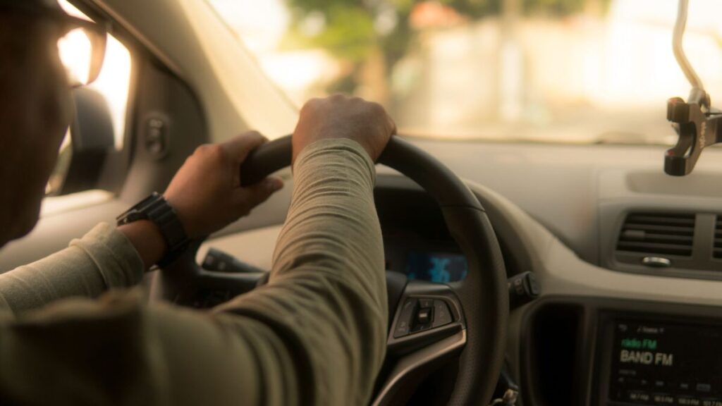 A driver's hands rest on a steering wheel.